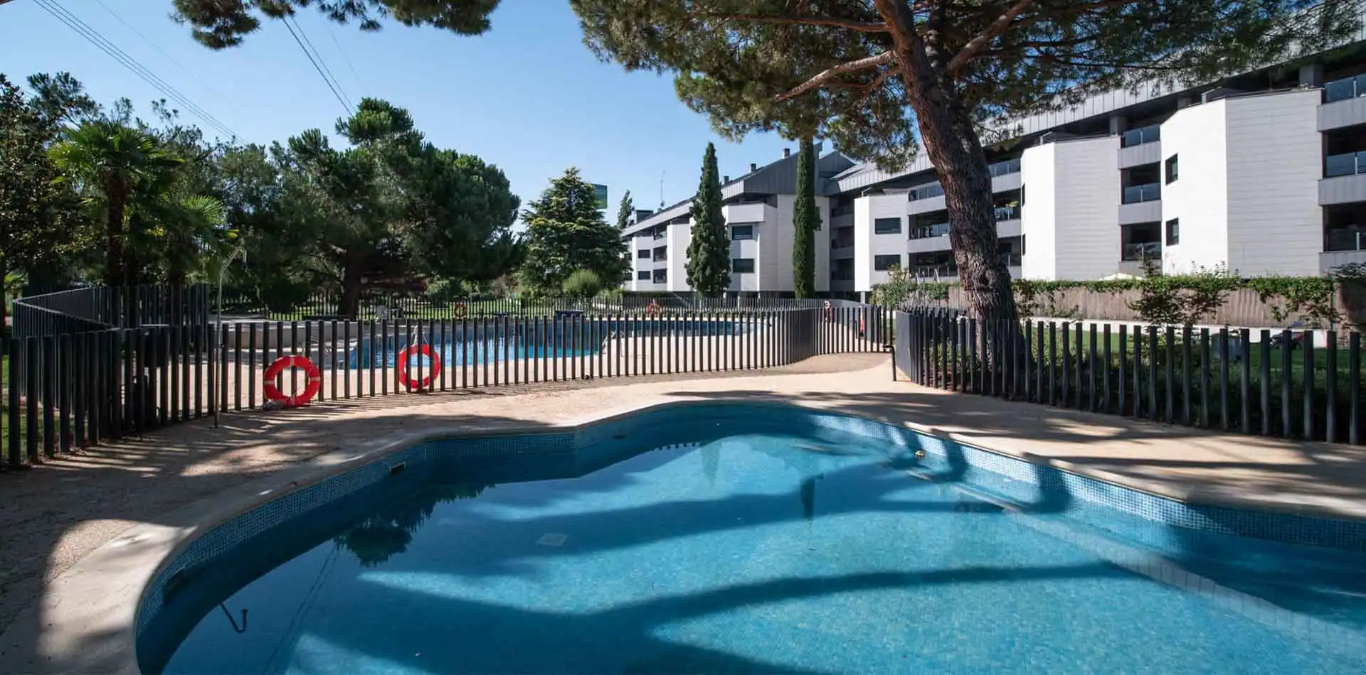 Piscina perfecta para refrescarte en verano en Lagos Park con fachada de fondo y viviendas con amplias terrazas.