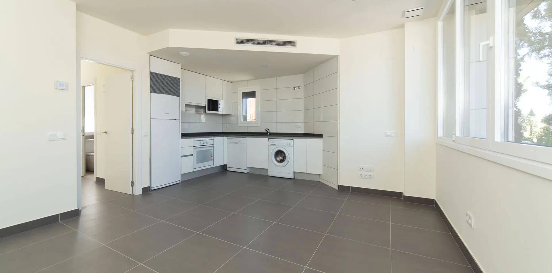 Cocina equipada en luminoso apartamento con suelos porcelánico gris y paredes blancas en Edificio La Estación Las Rozas de Madrid
